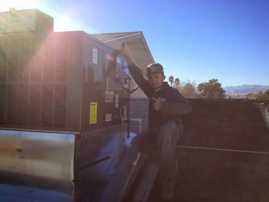 HVAC technician performing AC Tune-Up on a rooftop unit in Raisin
